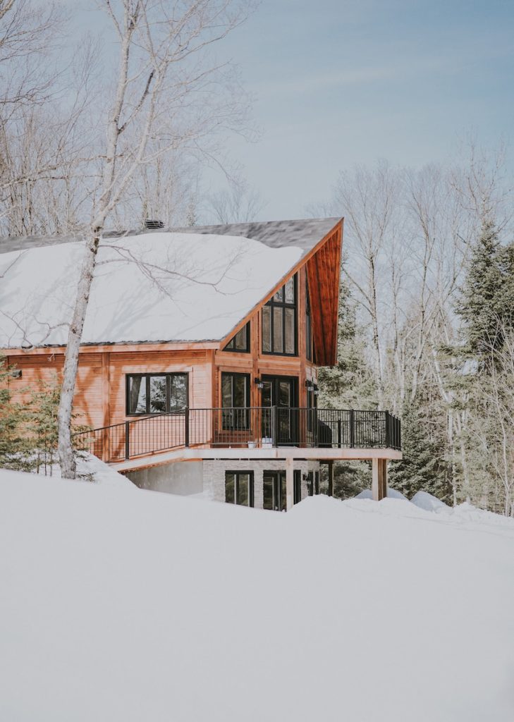 beige und weißes Holzhaus umgeben von schneebedecktem Feld während des Tages